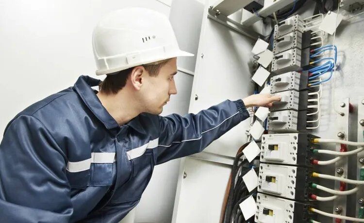 Handwerker guckt sich einen Technikschrank an.