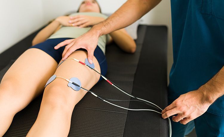 Jemand behandelt die Oberschenkelmuskeln mit einer Stromtherapie. Jemand behandelt die Oberschenkelmuskeln mit einer Stromtherapie.