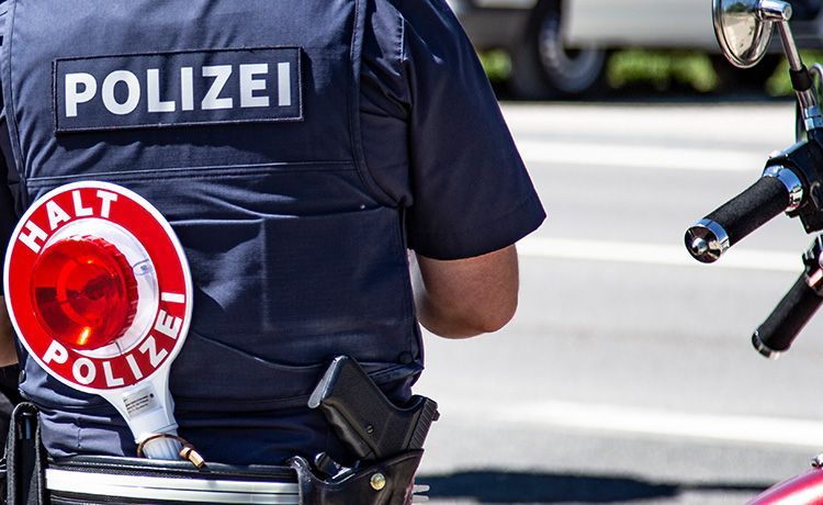 Junger Polizist von hinten mit Polizeikelle in der hinteren Hosentasche.