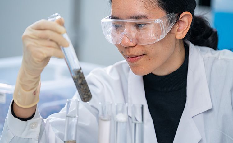 Junge Frau untersucht Gesteinsproben in einem Reagenzglas. Junge Frau untersucht Gesteinsproben in einem Reagenzglas.