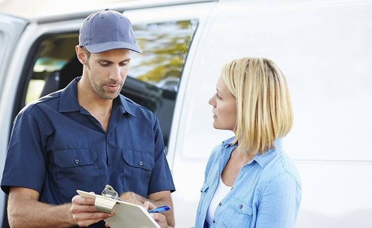 Frau unterzeichnet einen Lieferschein von einem Servicefahrer.