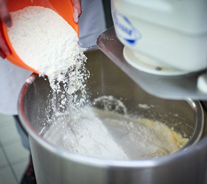 Jemand schüttet Mehl in einen Eimer.