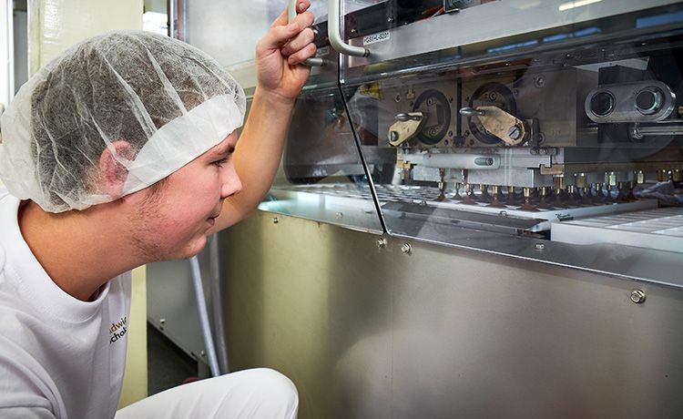 Azubi guckt sich eine Schokoladenmaschine an.