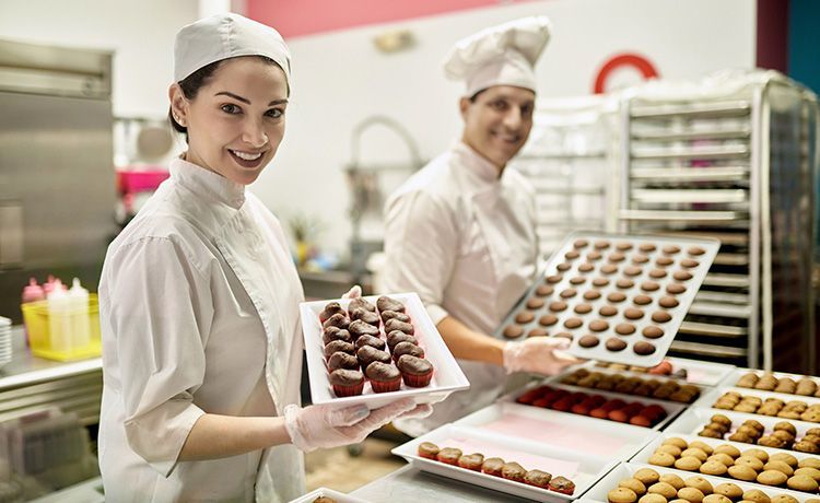 Junge Frau hält Pralinen in der Hand und steht in einer Küche. Junge Frau hält Pralinen in der Hand und steht in einer Küche.