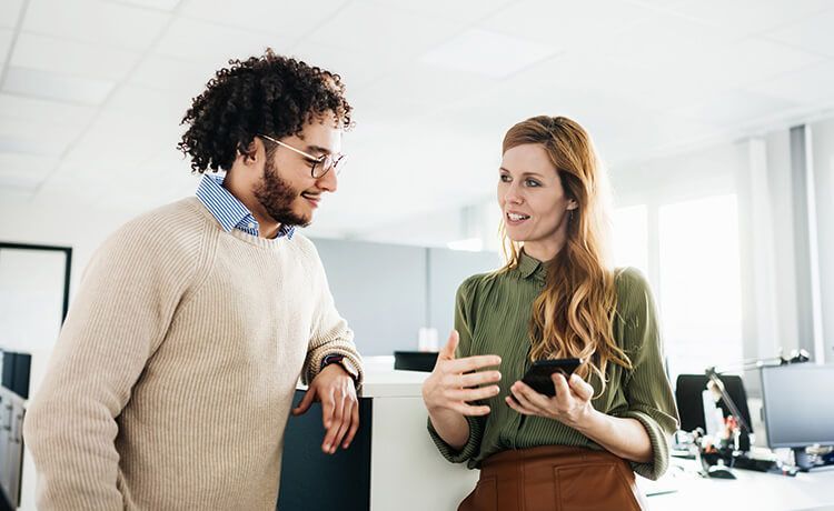 Zwei Verwaltungsfachangestellte stehen im Büro und sprechen über Verwaltungsaufgaben