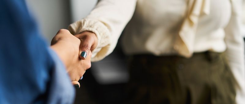 Chefin und Bewerber beschließen Ausbildungsvertrag mit Handschlag Chefin und Bewerber beschließen Ausbildungsvertrag mit Handschlag