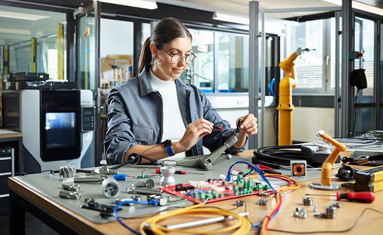 Junge Mechatronikerin arbeitet mit elektrischen Komponenten.