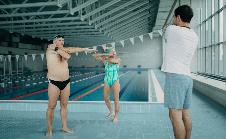 Fachangestellter für Bäderbetriebe zeigt Stretching-Übungen.