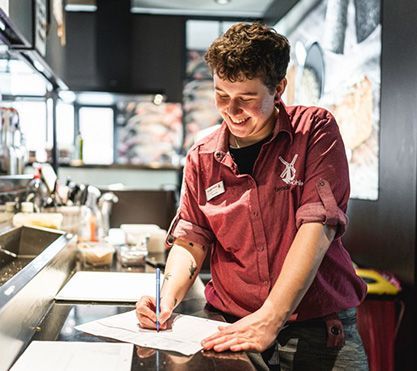 Frau in einer Bäckerei schreibt etwas auf.