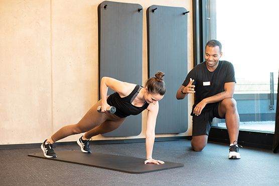 Eine Frau beim Sport und ein Fitnesstrainer.