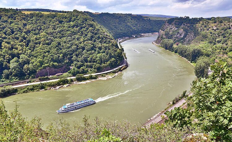 Frachtschiff und Passagierschiff fahren auf einem Fluss.