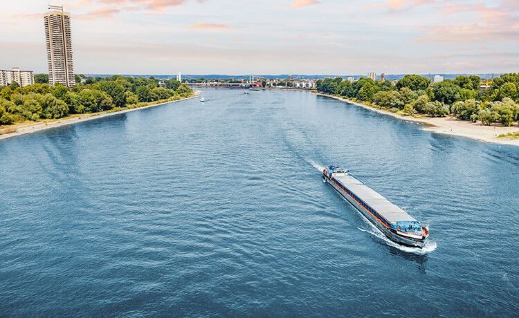 Binnenschiffer fährt mit Frachtschiff über den Rhein bei Köln.