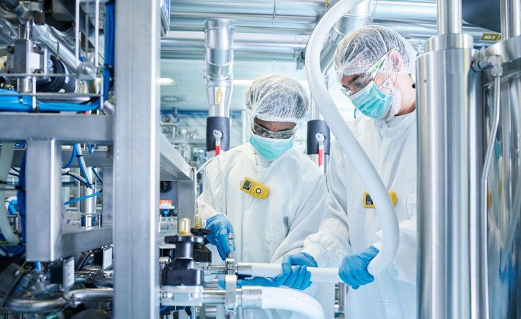 Zwei Chemikanten bedienen eine Produktionsanlage.