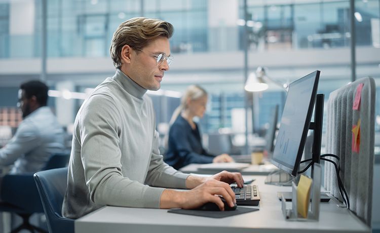 Data Analyst sitzt am PC im Büro und führt eine Datenanalyse durch.