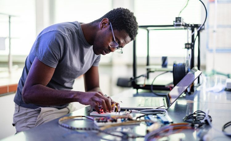 Junger Mann arbeitet mit elektrotechnischen Gegenständen.