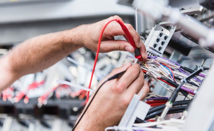 Detail mit Händen, die an einer Kabelkonstruktion arbeiten
