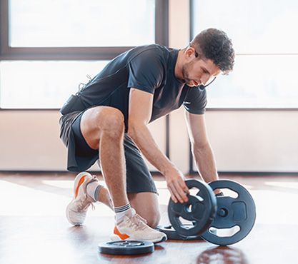 Fitnesstrainer mit Hantelscheiben bei der Arbeit.