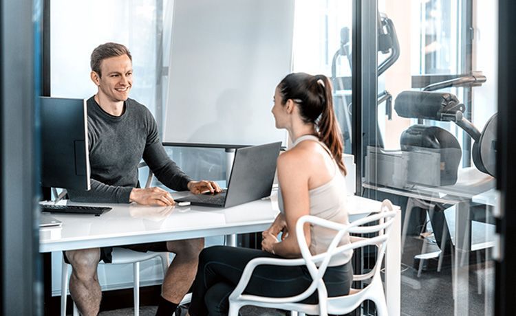 Fitnesstrainer berät Kundin.
