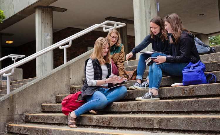 Studierende des dualen Studiums Gesundheitsmanagement sitzen auf einer Treppe und reden miteinander. Studierende des dualen Studiums Gesundheitsmanagement sitzen auf einer Treppe und reden miteinander.