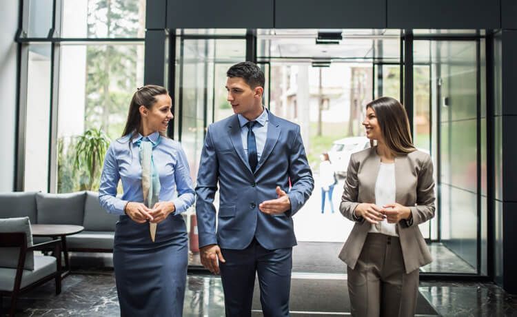 Hotelmanager und zwei Mitarbeitende laufen in ein Hotel.