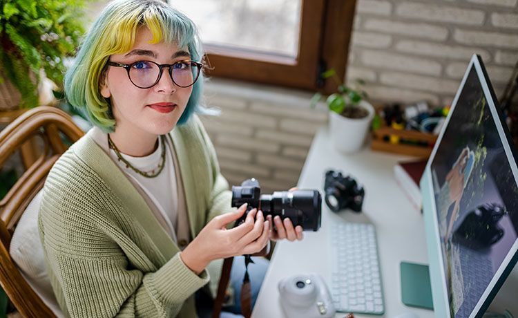 Junge Frau mit bunten Haaren hält Kamera in der Hand.