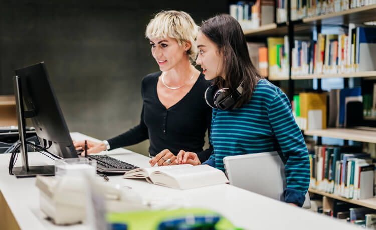 Studierende arbeiten am Computer für das duale Studium Sportmanagement.