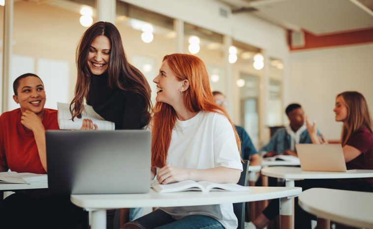 Drei Studentinnen gucken auf einen Laptop.