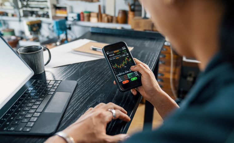 Mann beobachtet Aktienhandel auf dem Smartphone.