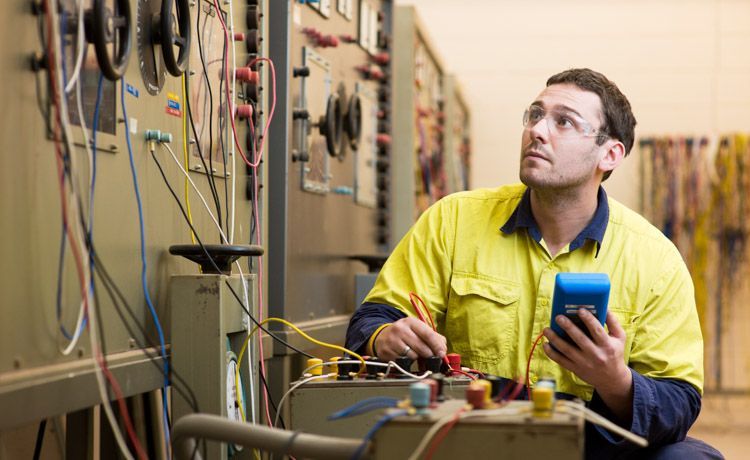Ein junger Elektroanlagenmonteur bei der Arbeit.