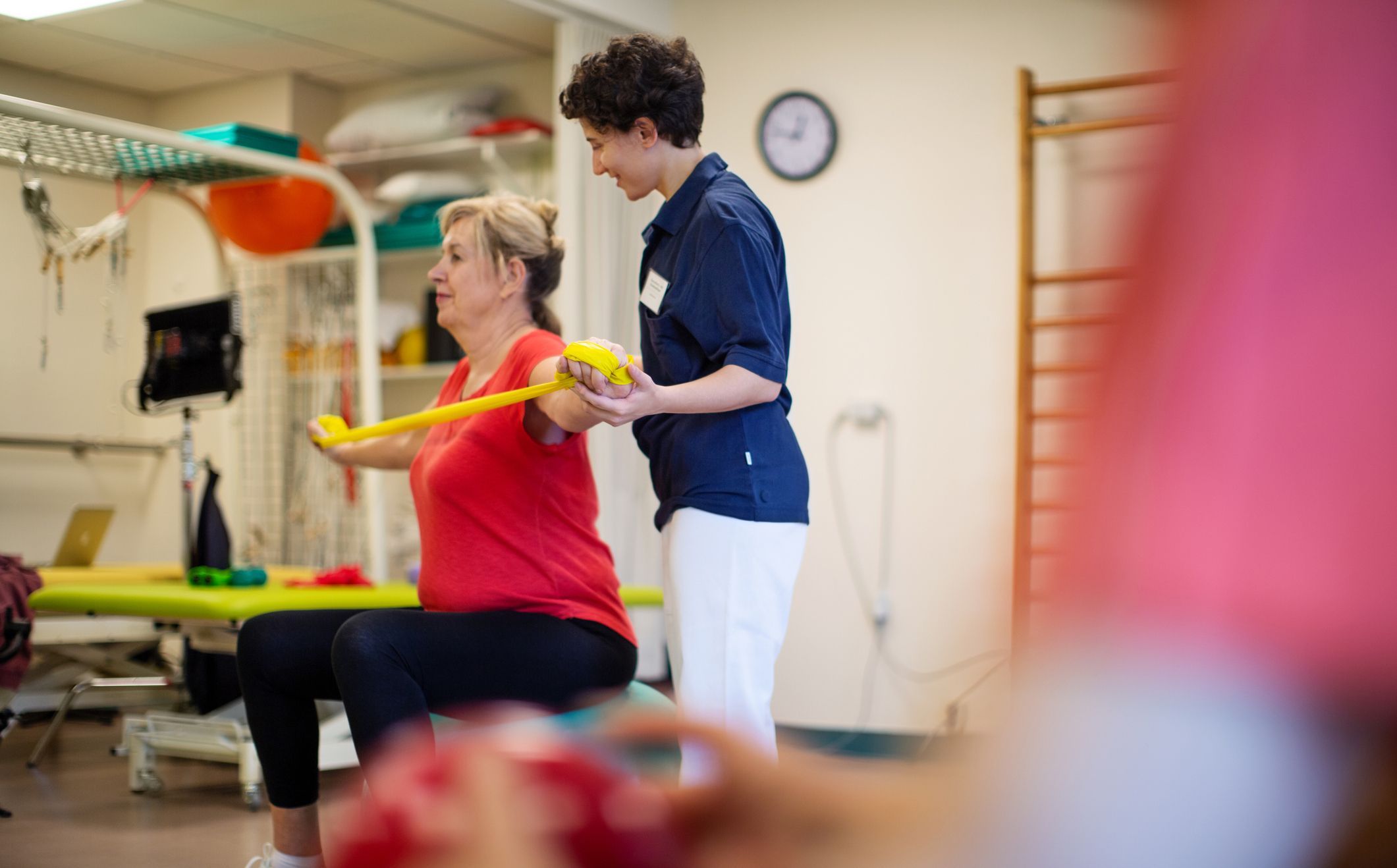Ergotherapeutin hilft Patientin mit Terraband.