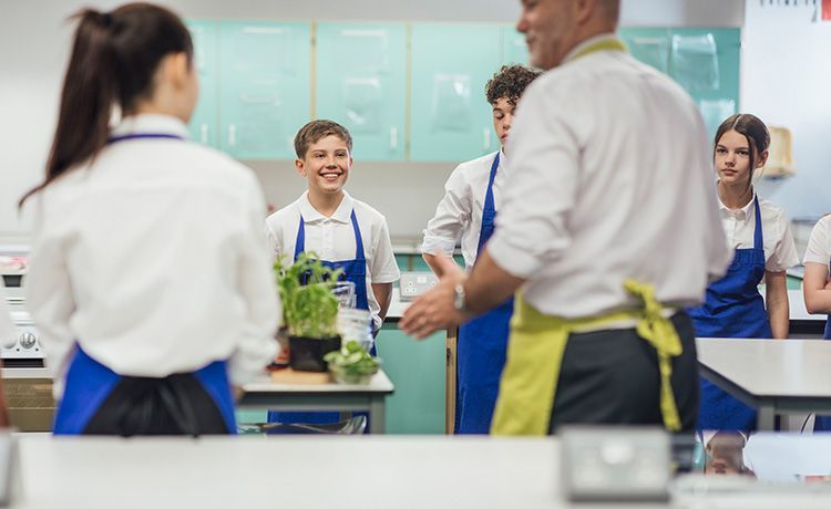 Ernährungsberater gibt einen Kochkurs an einer Schule und klärt Schüler über gesunde Ernährung auf.