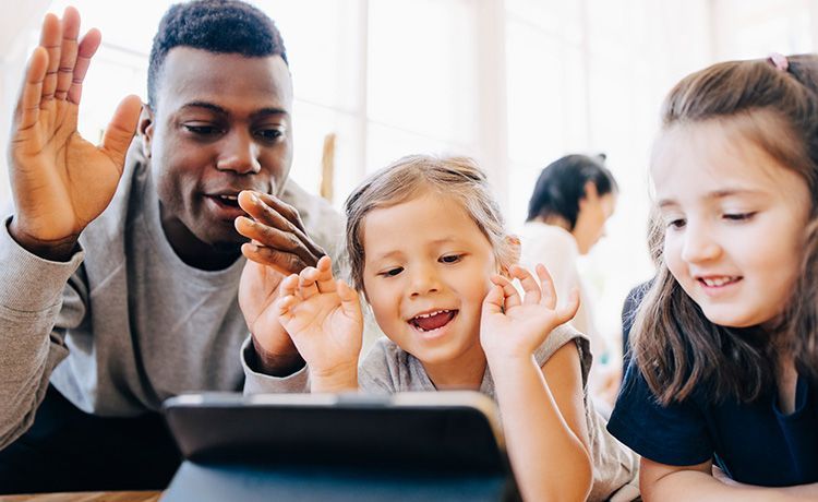 Ein Erzieher übt mit Kindern am Tablet.