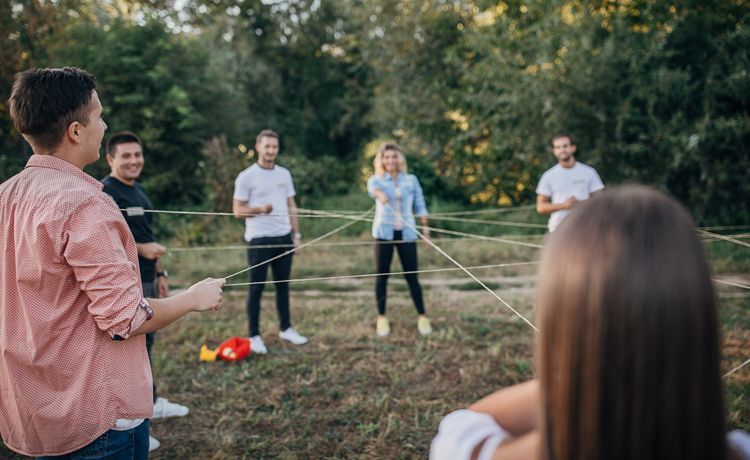 Junge Erwachsene spielen auf einer Wiese Spiel zum Kennenlernen.