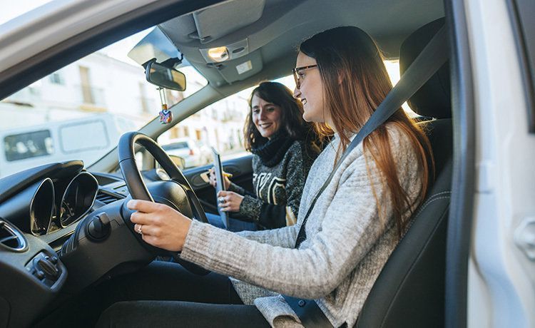 Junge Frau nimmt Fahrstunden und wird von ihrer Fahrlehrerin begleitet. 