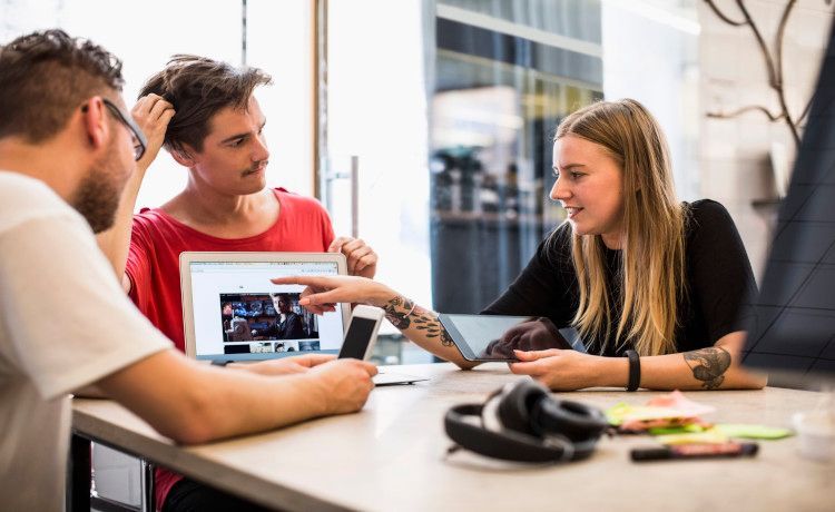 Drei Webdesigner diskutieren das Design einer Website. Drei Webdesigner diskutieren das Design einer Website.