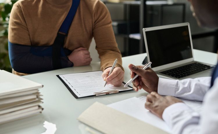 Kaufmann im Gesundheitswesen füllt mit Patient ein Formular aus.