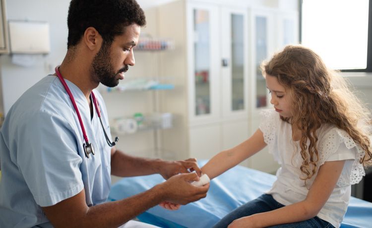 Kinderkrankenpfleger versorgt Wunde eines Mädchens