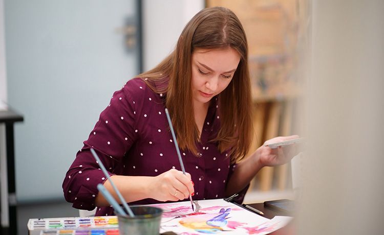 Junge Frau malt an einem Tisch. Junge Frau malt an einem Tisch.