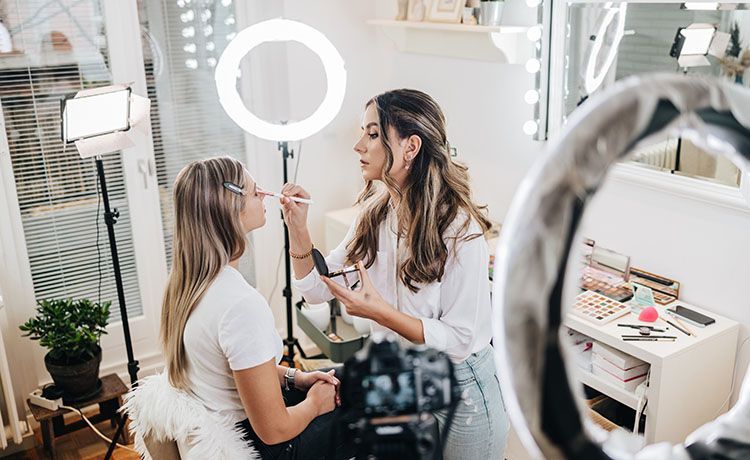 Make-up-Artistin schminkt Kundin zum Fotoshooting und dreht nebenbei ein Video für Social Media Make-up-Artistin schminkt Kundin zum Fotoshooting und dreht nebenbei ein Video für Social Media