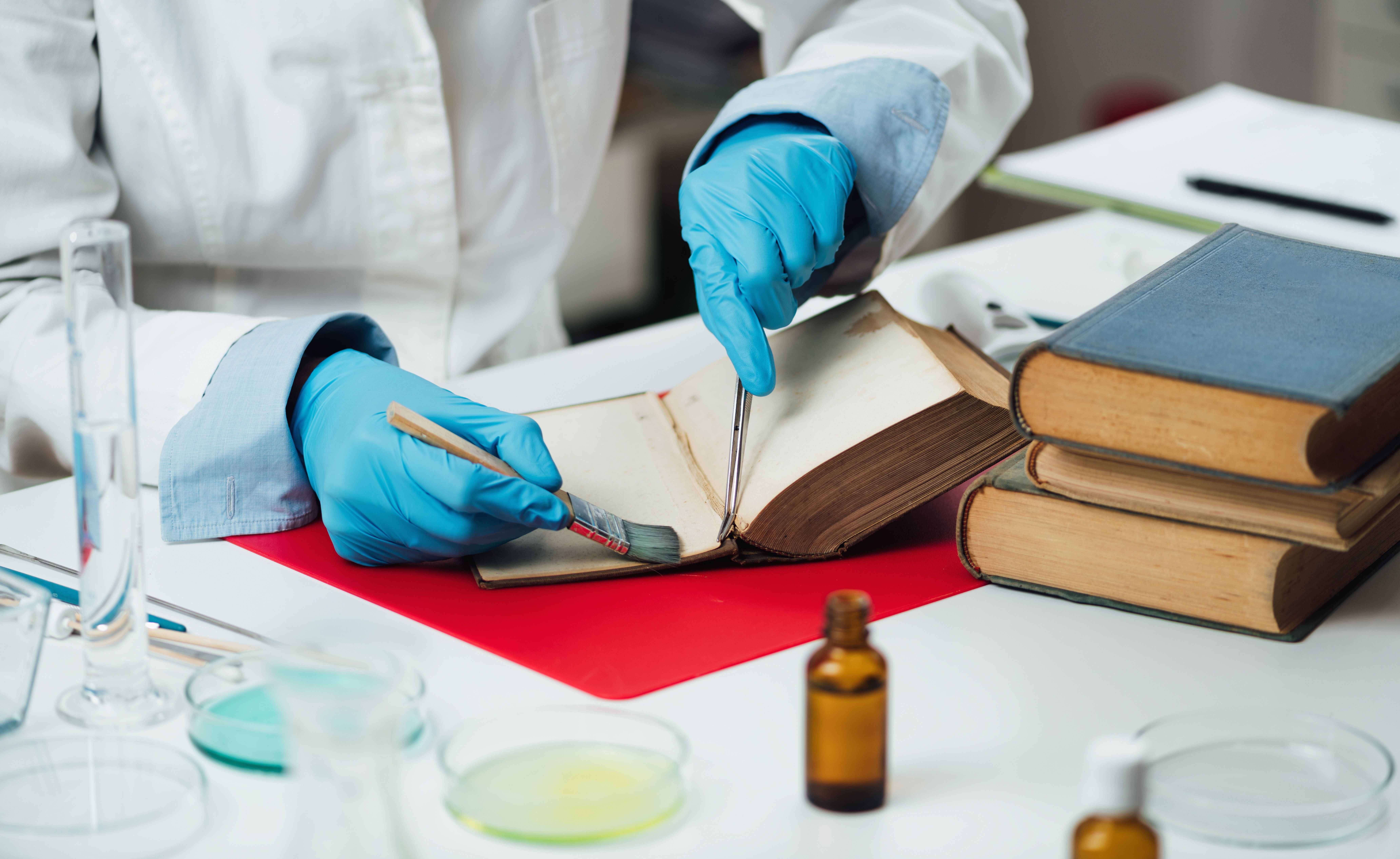 Buchrestaurator repariert beschädigte Seiten in einem antiken Buch. Buchrestaurator repariert beschädigte Seiten in einem antiken Buch.