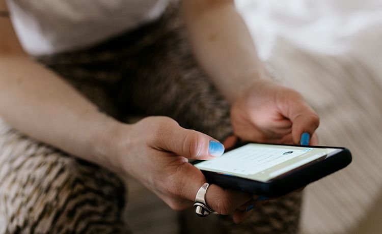 Social Media Managerin hält Smartphone in der Hand und macht Community Management.