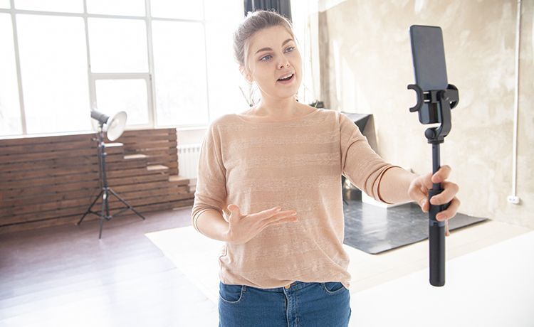 Social Media Managerin hält ein Gimble mit Smartphone in der Hand und dreht Content.