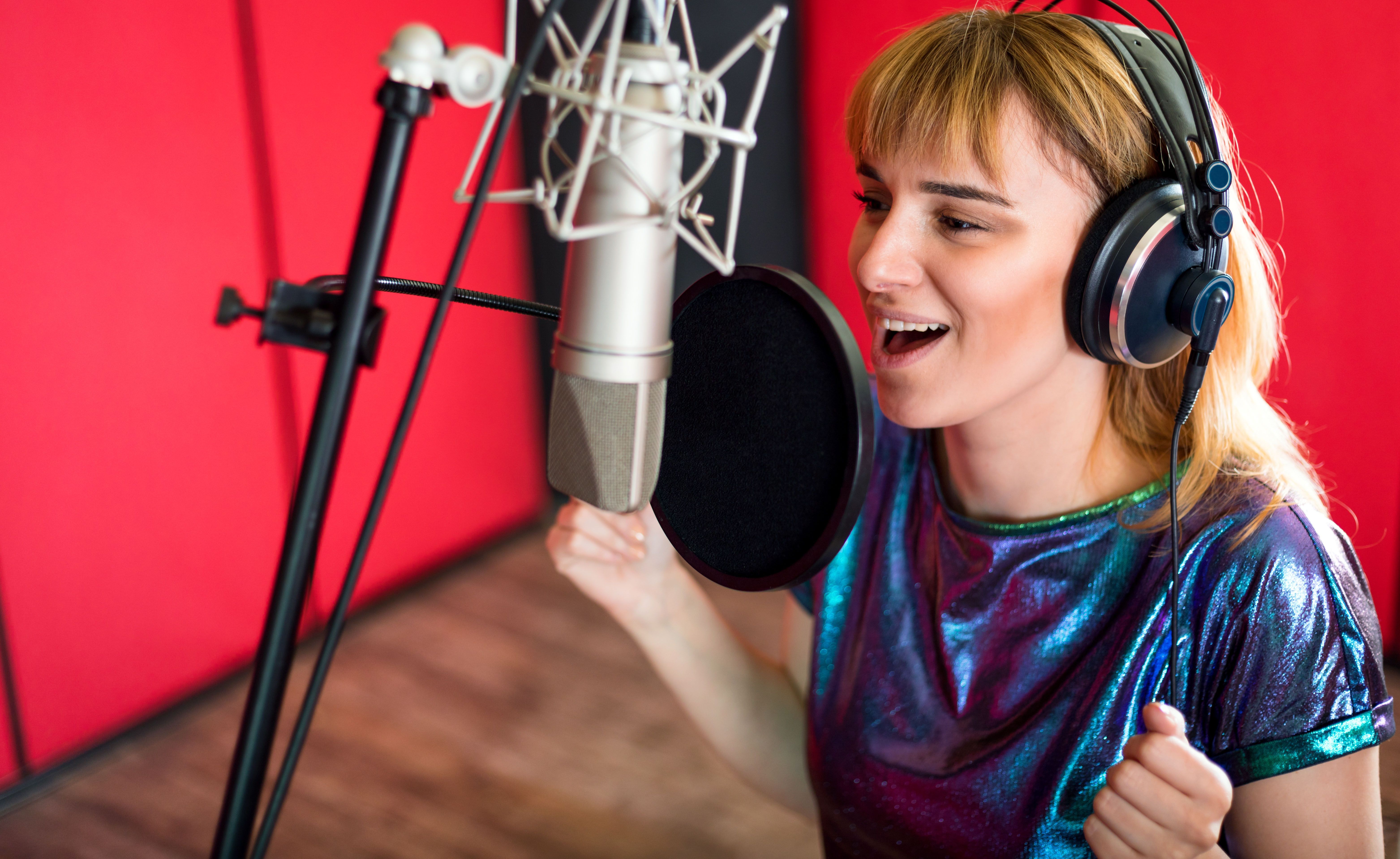 Frau spricht enthusiastisch in ein Mikrofon im Tonstudio