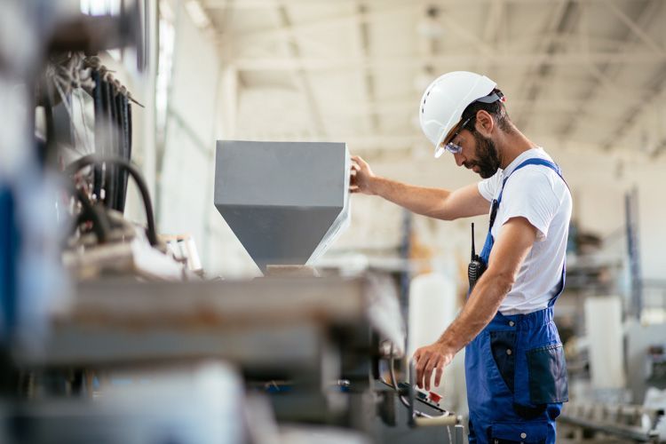 Ein Verfahrensmechaniker für Kunststoff- und Kautschuktechnik bedient eine Maschine.