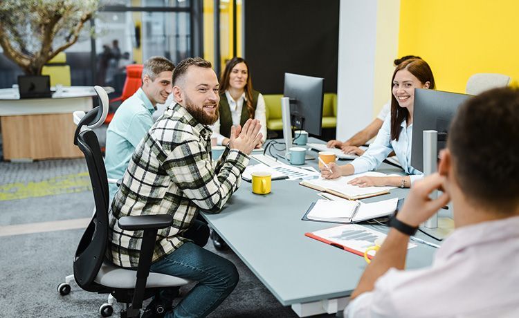 Betriebswirt sitzt mit Kollegen an einem Tisch und besprechen betriebswirtschaftliche Themen.