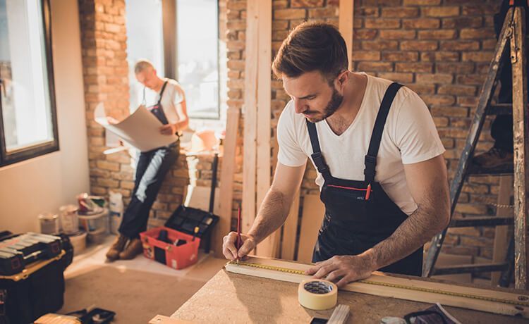 Zwei Zimmerer sind auf der Baustelle und messen Holz. Zwei Zimmerer sind auf der Baustelle und messen Holz.
