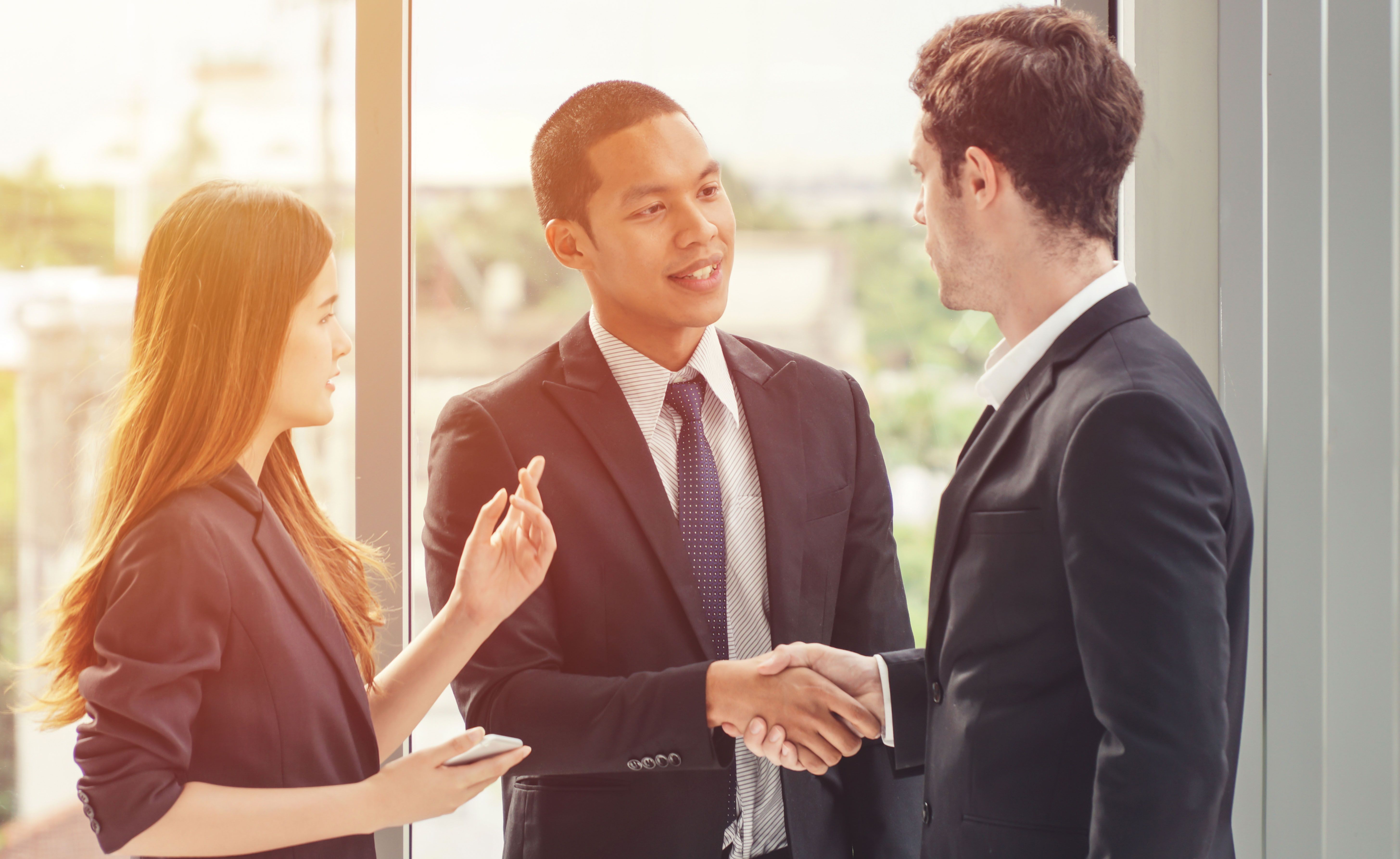 Junge Frau übersetzt ihrem Kollegen ein Gespräch mit ausländischem Partner