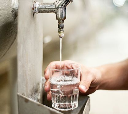 Umwelttechnologe für Wasserversorgung entnimmt Wasserprobe im Glas.
