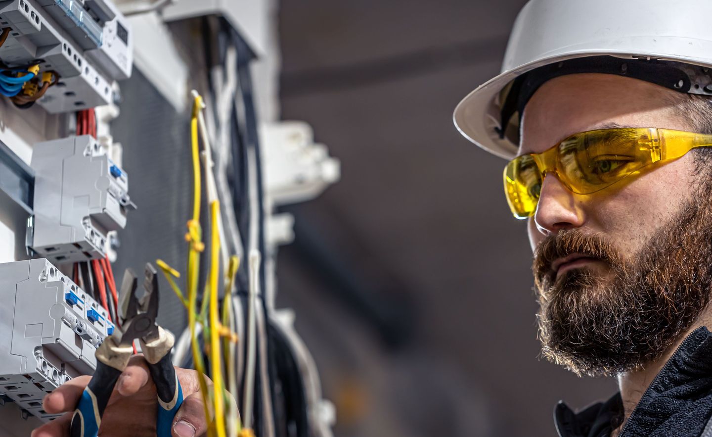 Elektroniker für Energie und Gebäudetechnik mit Schutzbrille und Helm bei der Arbeit.