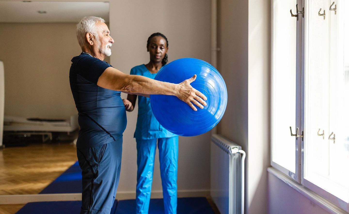 Ergotherapeutin betreut Mann mit Gymnastikball.